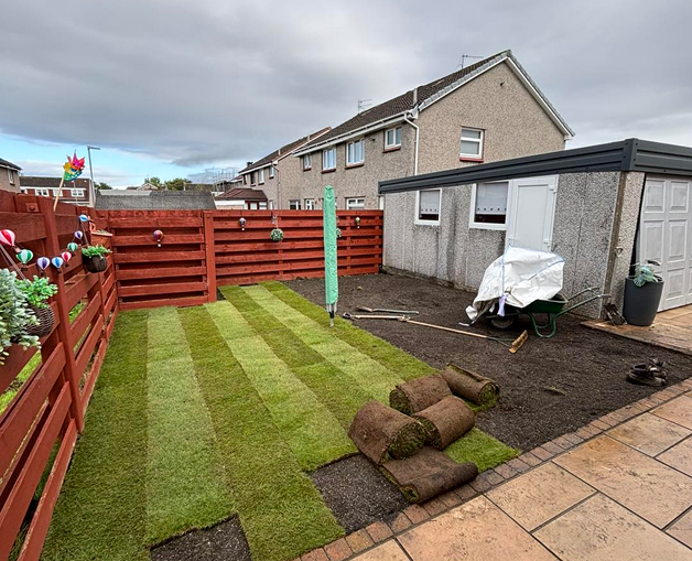 Back Garden with children's shoots and playthings.  The grass has punctured holes in it, this is the aeration process
